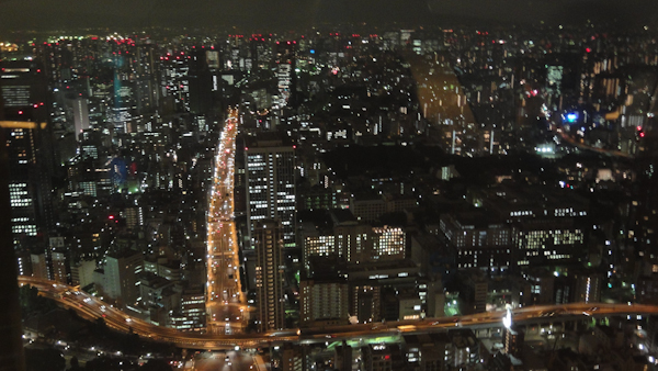 a view of tokyo at night with paths of light where major streets cross